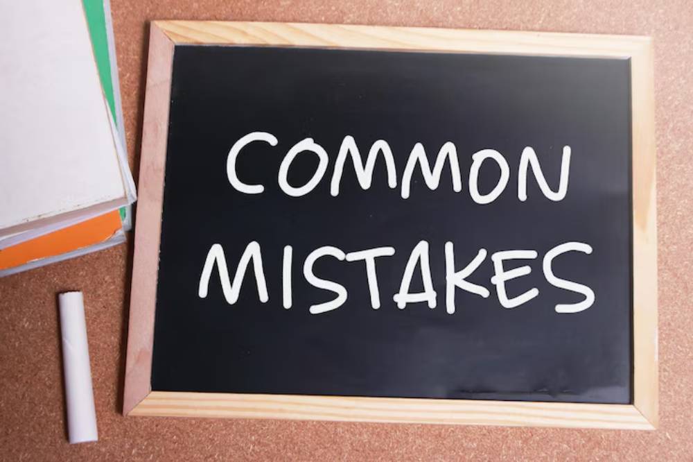 A black chalkboard with the words 'COMMON MISTAKES' written in white chalk, alongside books and a chalk piece.
