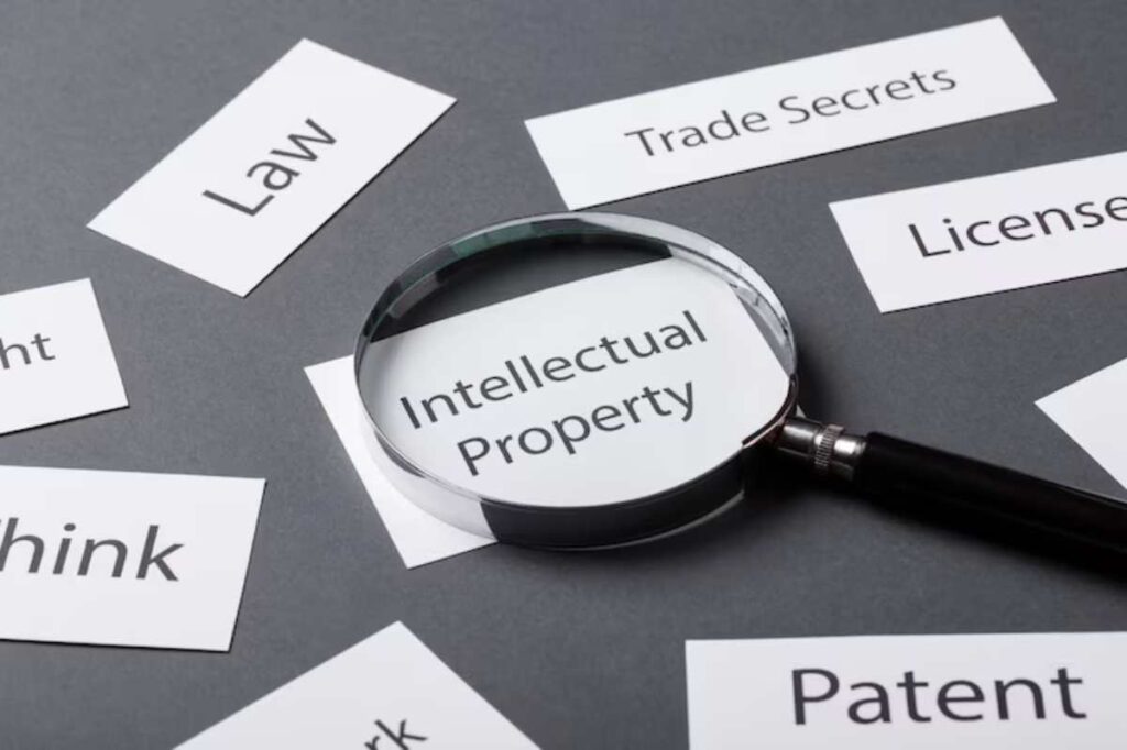 A magnifying glass focuses on the words 'Intellectual Property' surrounded by related terms like 'Law' and 'Patent'