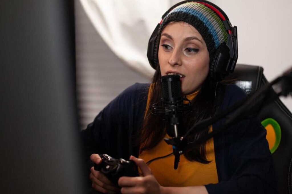 A gamer wearing headphones, focused on her gameplay, holds a gaming controller in a cozy, well-lit gaming setup.
