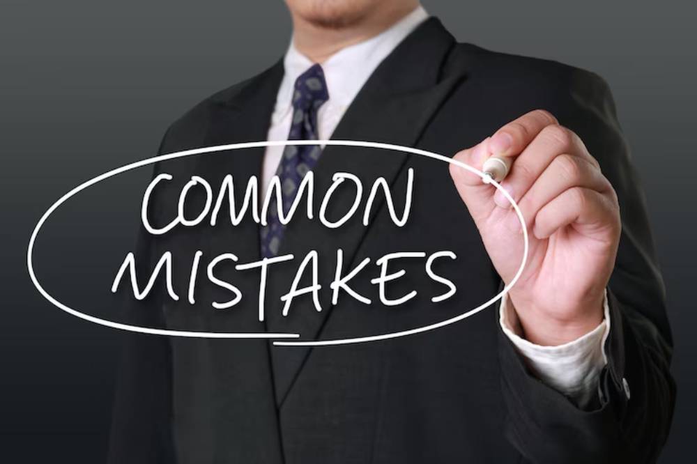 A businessman in a suit holds a marker, writing 'COMMON MISTAKES' in a circular outline against a dark background.