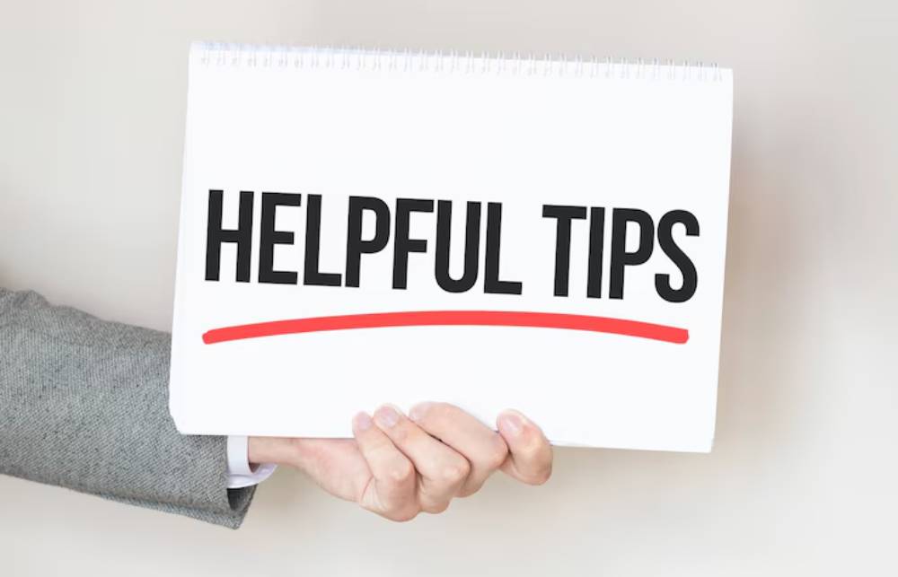 A person in a suit holds a sign that says 'HELPFUL TIPS' in bold black letters, underlined with a red line, against a light background.