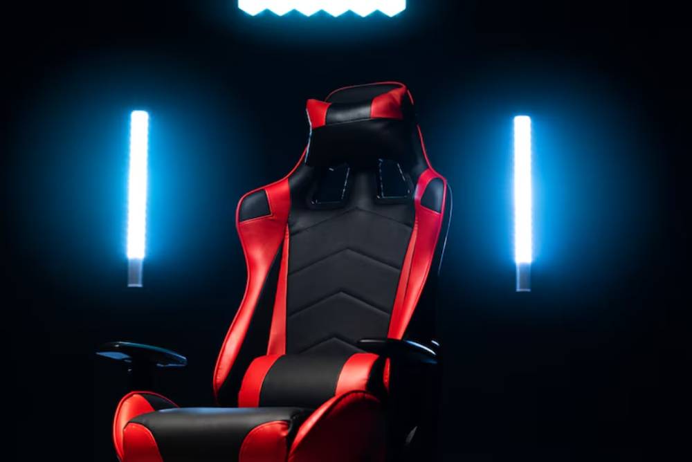 A sleek black and red gaming chair illuminated by blue LED lights, set against a dark background.
